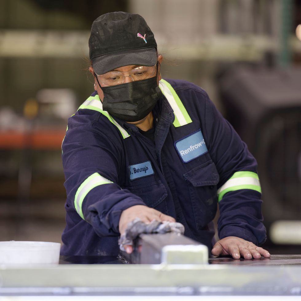 Renfrow+Co team member working with a metal surface showcasing expertise in custom metal fabrication and finishing in Houston