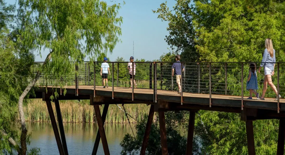 A group of visitors standing on the weathering steel and wooden deck, part of Renfrow+Co's High Island Sky Walk project, with a scenic view of the surrounding lake A group of visitors standing on the weathering steel and wooden deck, part of Renfrow+Co's High Island Sky Walk project, with a scenic view of the surrounding lake