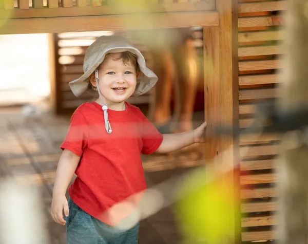 Close-up of a young boy smiling while holding onto a wooden column of a natural structure at the Houston Botanic Garden Close-up of a young boy smiling while holding onto a wooden column of a natural structure at the Houston Botanic Garden