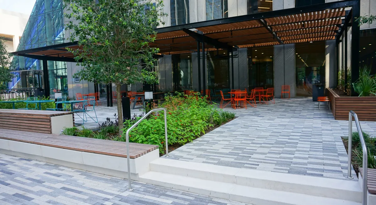 Outdoor seating area at JPMorgan Chase Tower with orange chairs and tables, featuring stainless steel railings designed by Renfrow+Co