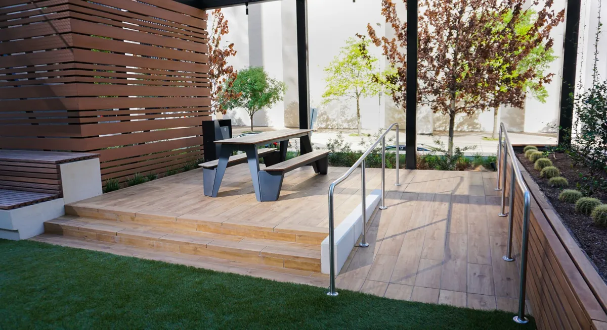 Outdoor wooden platform designed by Renfrow+Co with a picnic table, stainless steel railings, and a modern slatted wood fence