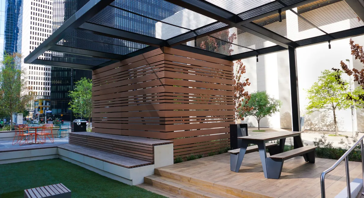 A modern outdoor seating area at JPMorgan Chase Tower with wood slat walls and benches, created by Renfrow+Co, complete with stainless steel railings and sleek wooden decking