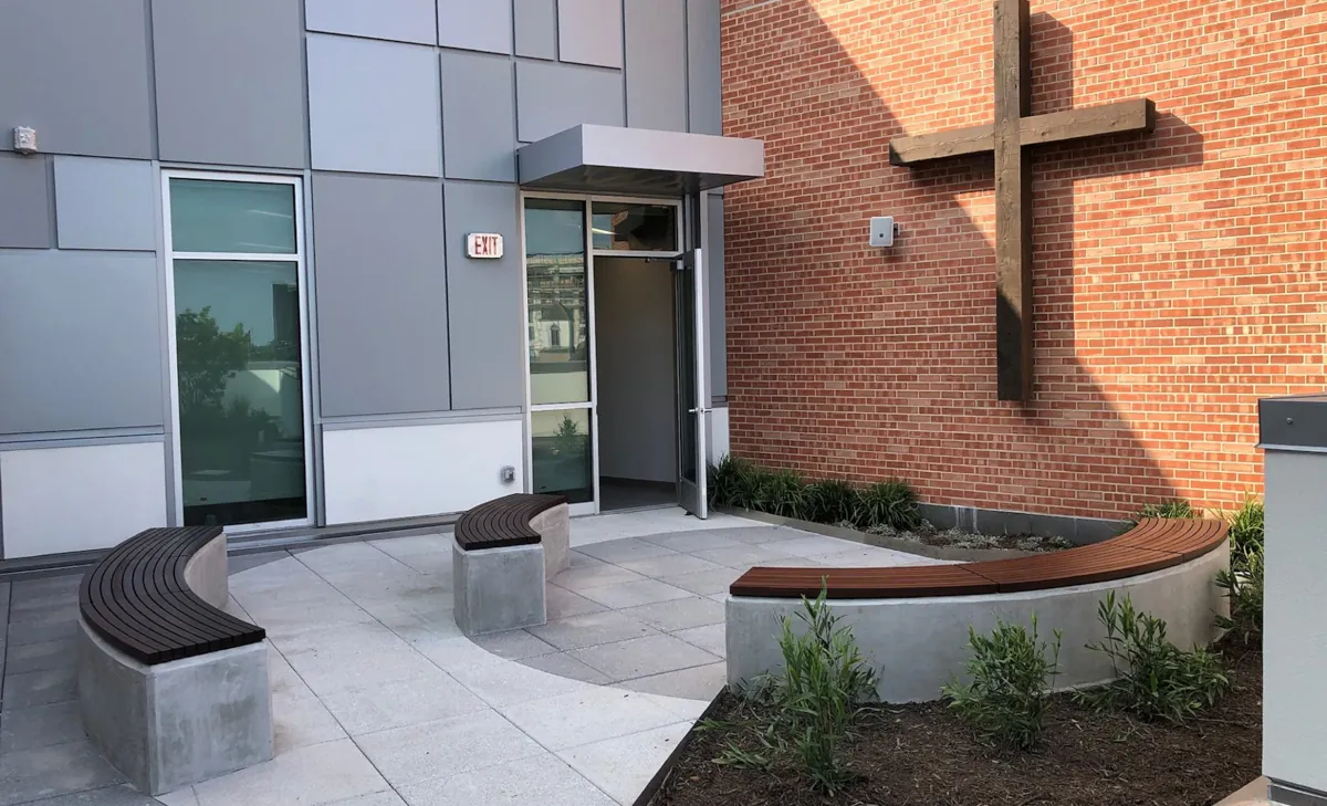 Outdoor seating area with a wall-mounted Accoya wood cross fabricated by Renfrow+Co at River Oaks Baptist School